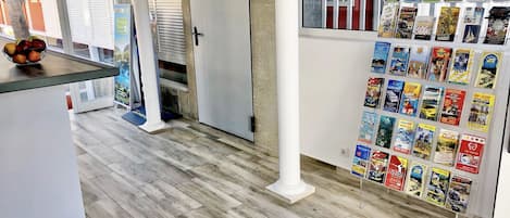 A modern interior with a wooden floor, a white pillar, and a wall displaying various travel brochures.