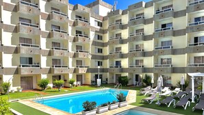 Un edificio residencial de varios pisos con piscina y zona de estar al aire libre.