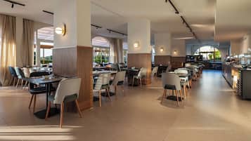 Un restaurante espacioso con varias mesas y sillas, ventanas amplias y una decoración de diseño moderno.