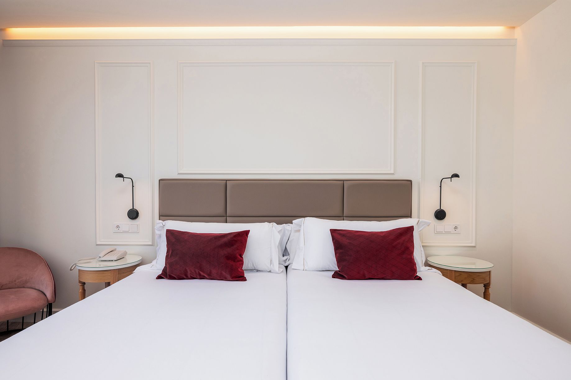Une chambre d’hôtel avec un grand lit, deux tables de chevet, un téléphone et une chaise.