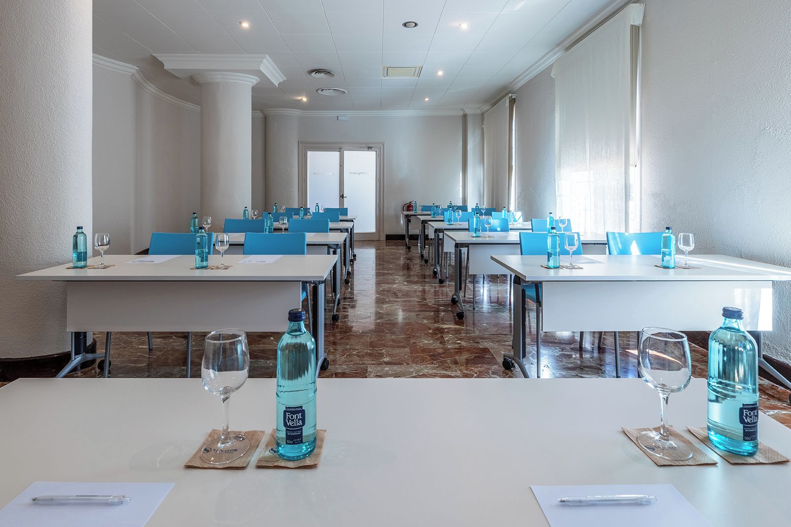Une salle de conférence équipée de tables, de chaises et de bouteilles d’eau.