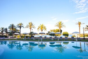 Una piscina al aire libre, sombrillas, sillones reclinables de piscina