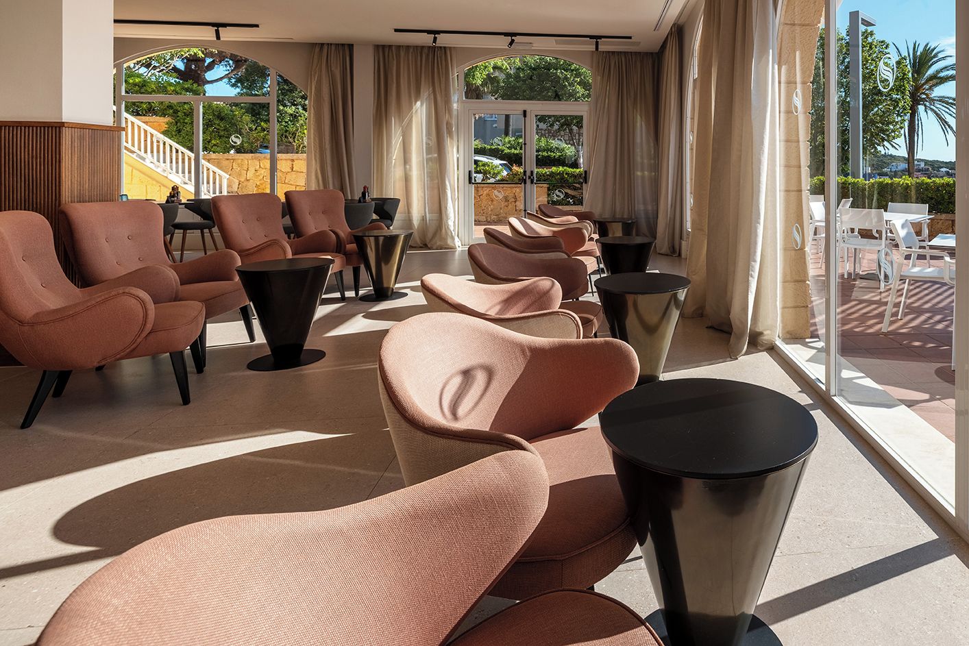 A hotel lobby with rows of seating, large windows, and a view of the outdoors.