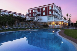 A hotel with a swimming pool, lounge chairs, and a staircase leading to the upper floors. - Senator Port Mahón (Mahón)