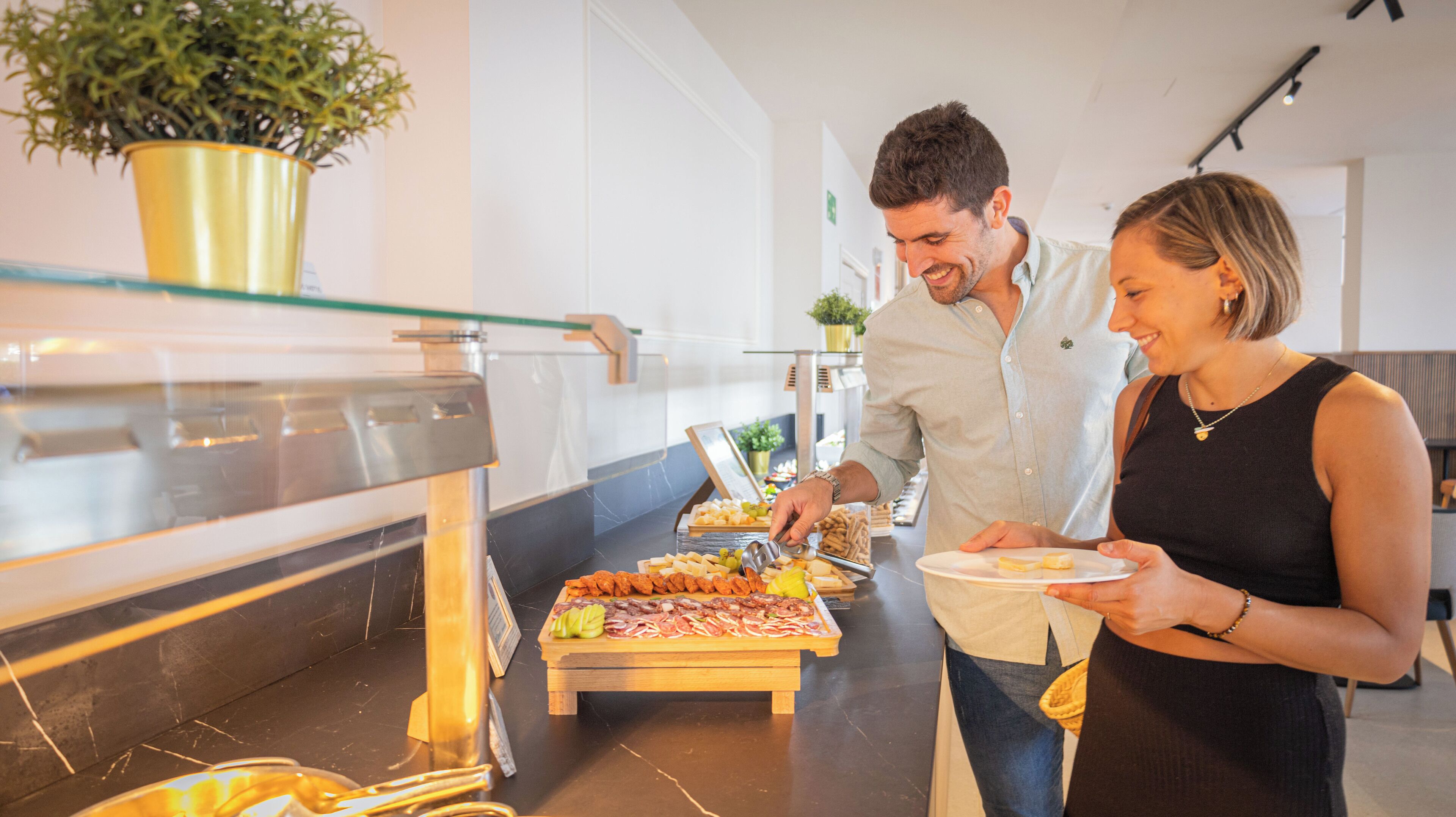 A buffet setup with various food items and a person serving.