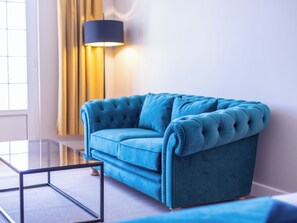 A blue sofa in a room with a glass coffee table and a floor lamp. - Senator Port Mahón (Mahón)
