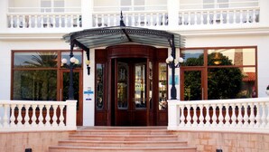 L’entrée d’un hôtel, avec une grande porte en bois, un porche et une balustrade blanche.