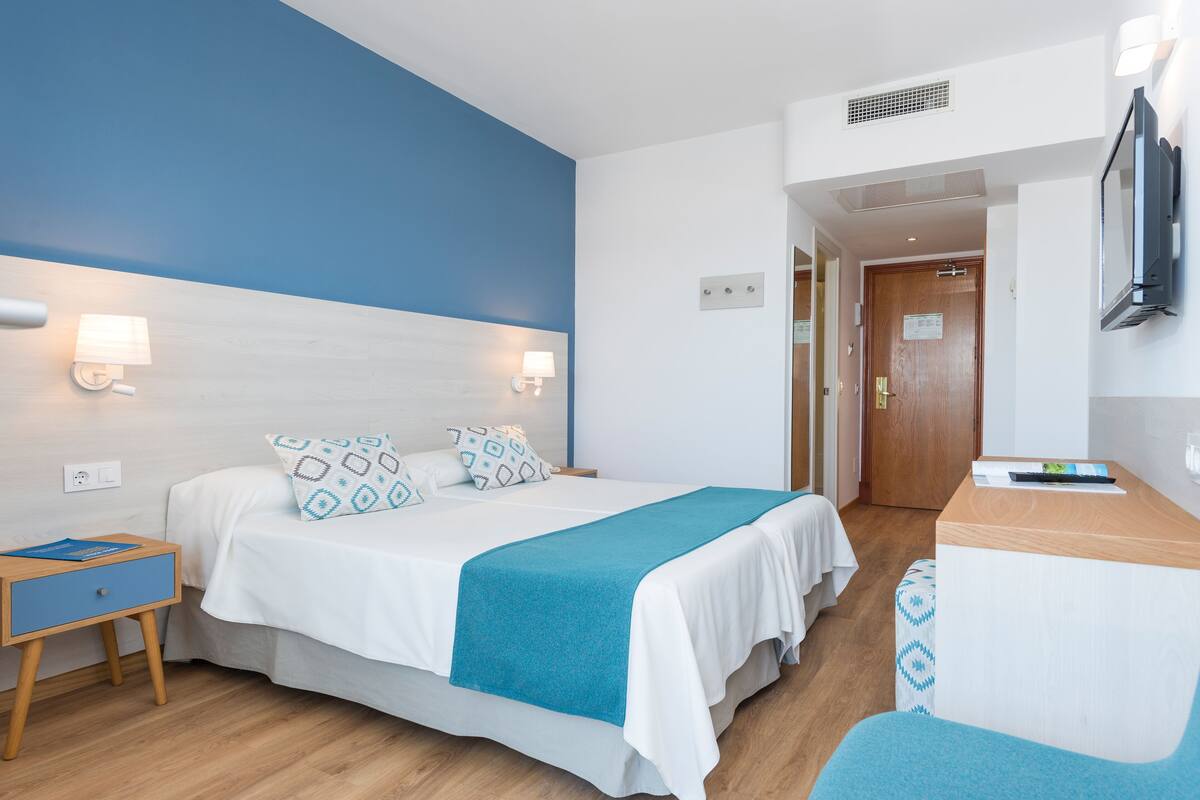Una habitación de hotel con cama, mesita de noche y escritorio con silla.
