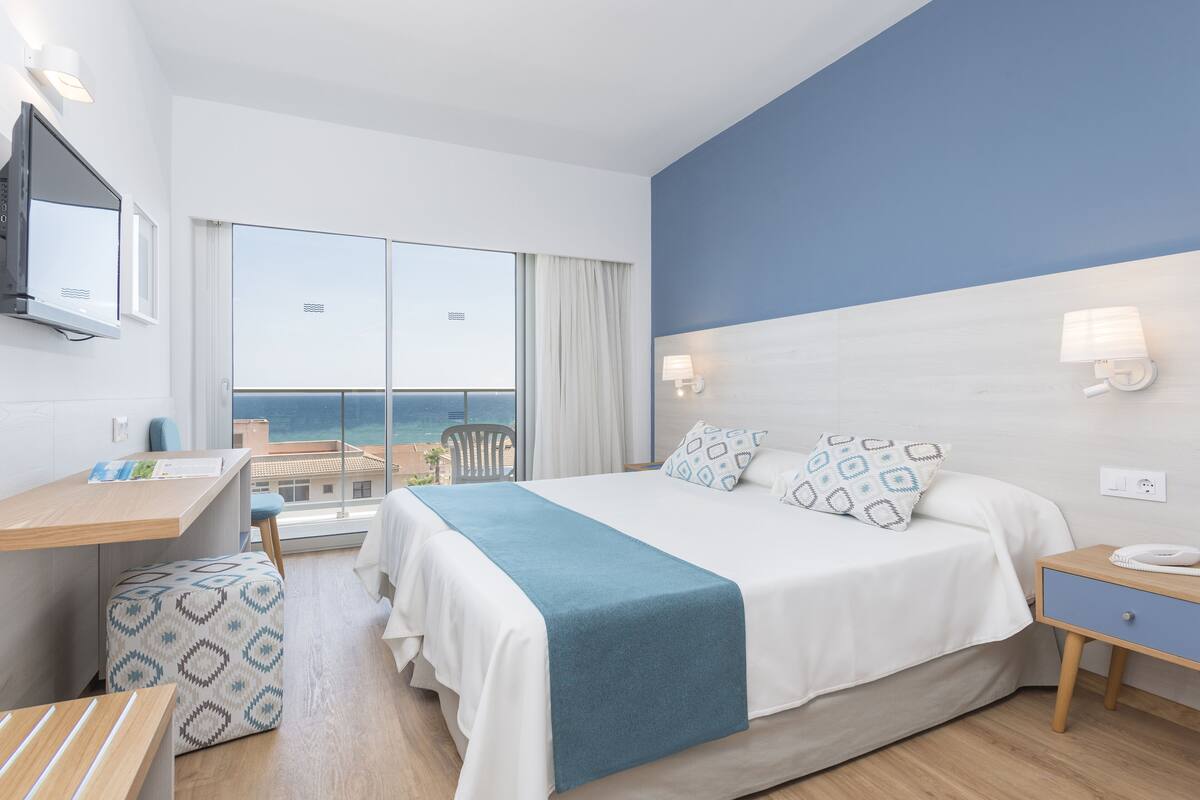 Una habitación de hotel moderna con una cama grande, un escritorio y vista al mar.