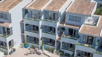 A multi-story hotel with a swimming pool, outdoor seating, and a view of the surrounding area.
