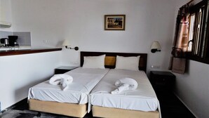 A hotel room with two beds, a small kitchenette, and a painting on the wall. - Blue Sea (Samos)