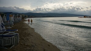 A beach with umbrellas and lounge chairs, a sandy shore, and a calm sea. - Yassen Mng Apartments (Nessebar)