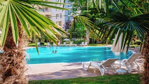 A swimming pool with lounge chairs and palm trees. - Yassen Mng Apartments (Nessebar)