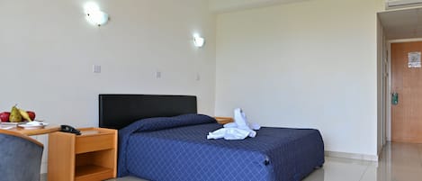 A hotel room with a bed, bedside table, and a small desk with a chair.