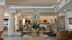 Un hall d’entrée spacieux, agrémenté d’une fontaine centrale richement décorée, d’un sol carrelé poli et d’un plafond haut avec des luminaires encastrés.