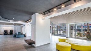 A modern interior with seating areas, a glass wall, and a sign for "Incredible University". - Anthea Hotel Apartments (Ayia Napa)