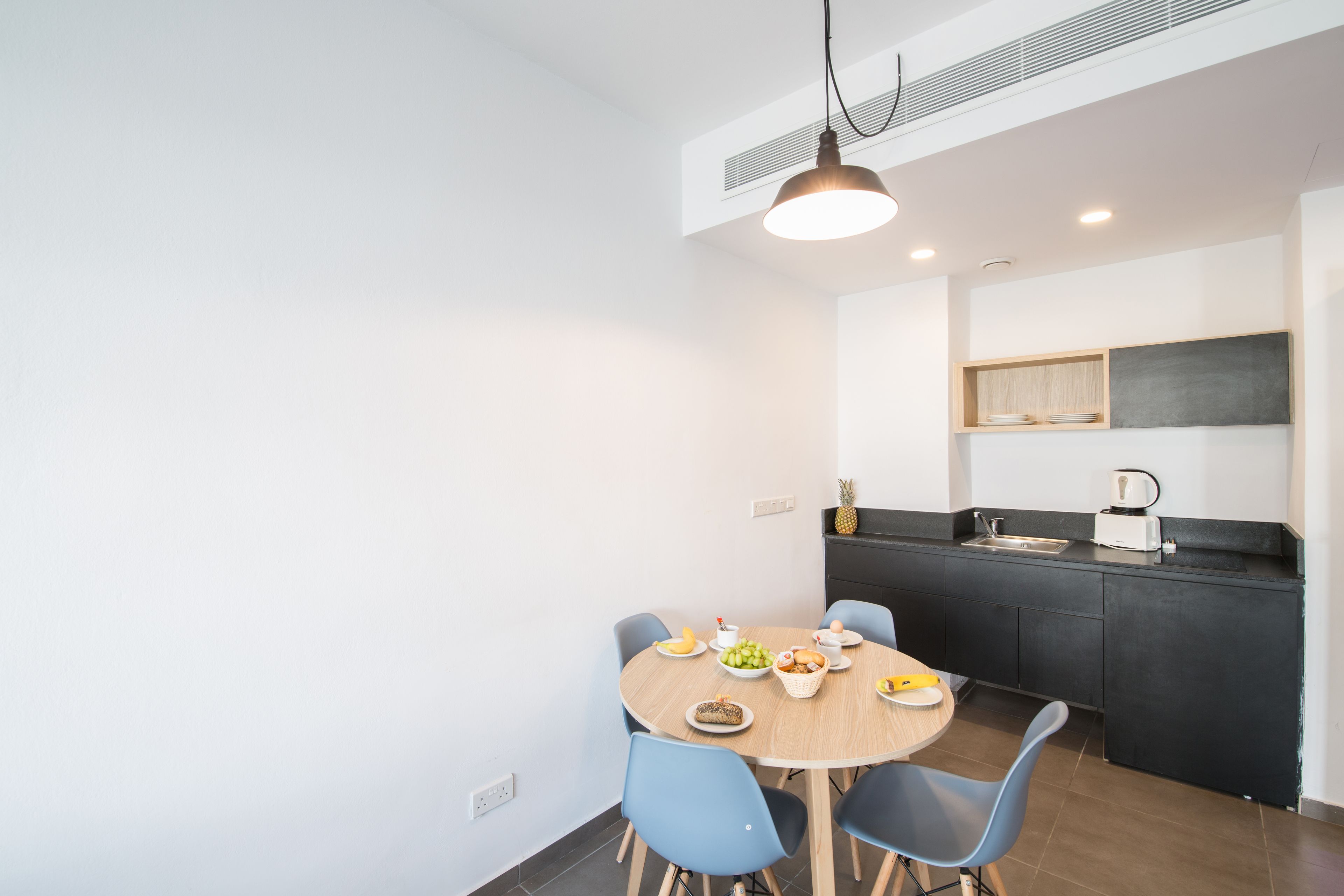 Una cucina moderna con un tavolo da pranzo rotondo, sedie blu e un piano di lavoro nero.