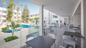 A modern hotel lobby with a pool view, outdoor seating, and a spacious layout. - Anthea Hotel Apartments (Ayia Napa)