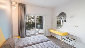 A modern bedroom with a bed, a desk, and a window overlooking a balcony.