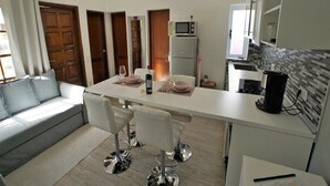A modern kitchen with a dining area, white appliances, and a grey tiled backsplash. - Bungalows Las Vegas Golf (San Bartolome de Tirajana)
