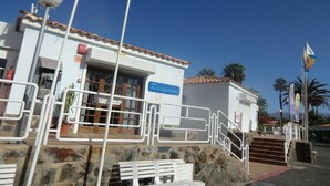 A building with a reception sign, a tiled roof, and a stone staircase leading to the entrance. - Bungalows Las Vegas Golf (San Bartolome de Tirajana)