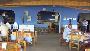 A restaurant with wooden tables and chairs, a stone counter, and blue walls. - Bungalows Las Vegas Golf (San Bartolome de Tirajana)