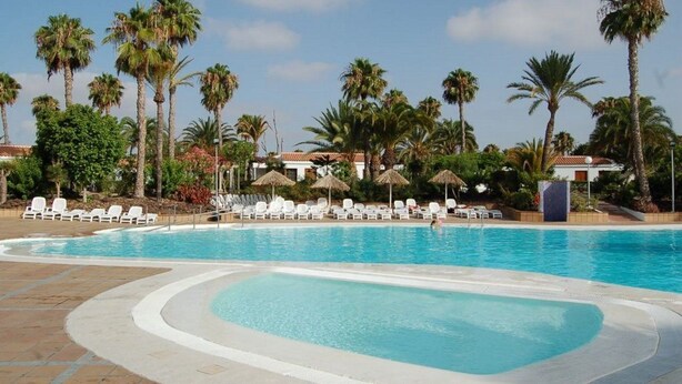 A swimming pool with lounge chairs and palm trees. - Bungalows Las Vegas Golf (San Bartolome de Tirajana)