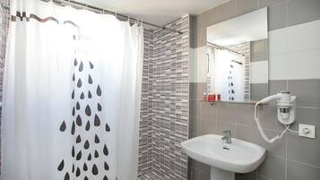 Un baño con cortina de ducha, paredes de azulejos, un lavabo y un espejo.