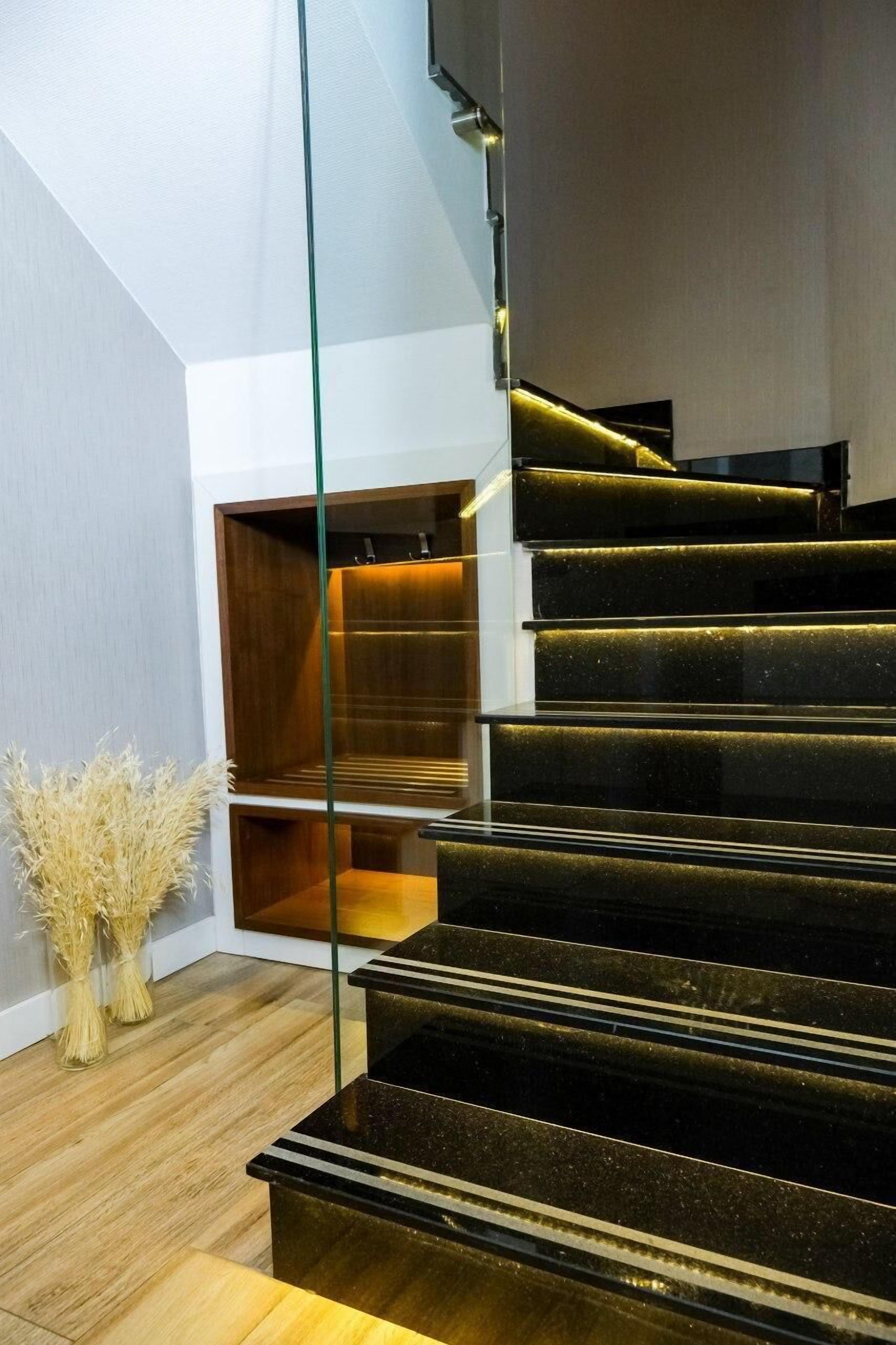 Una escalera moderna con barandillas de vidrio y escalones de madera.