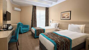 A hotel room with two beds, a desk, a chair, and a TV.