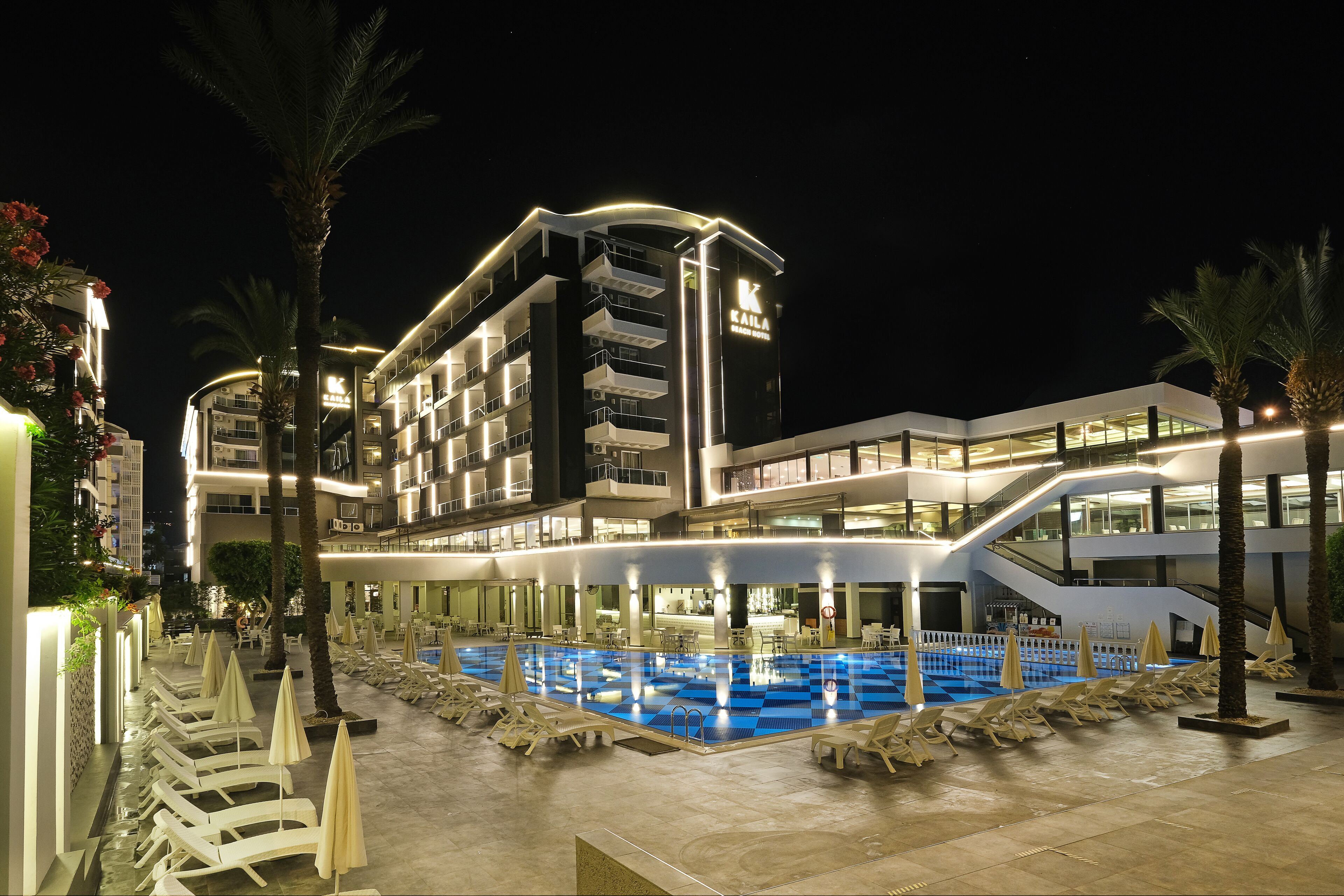 A modern hotel with a pool area, multiple floors, and outdoor seating.