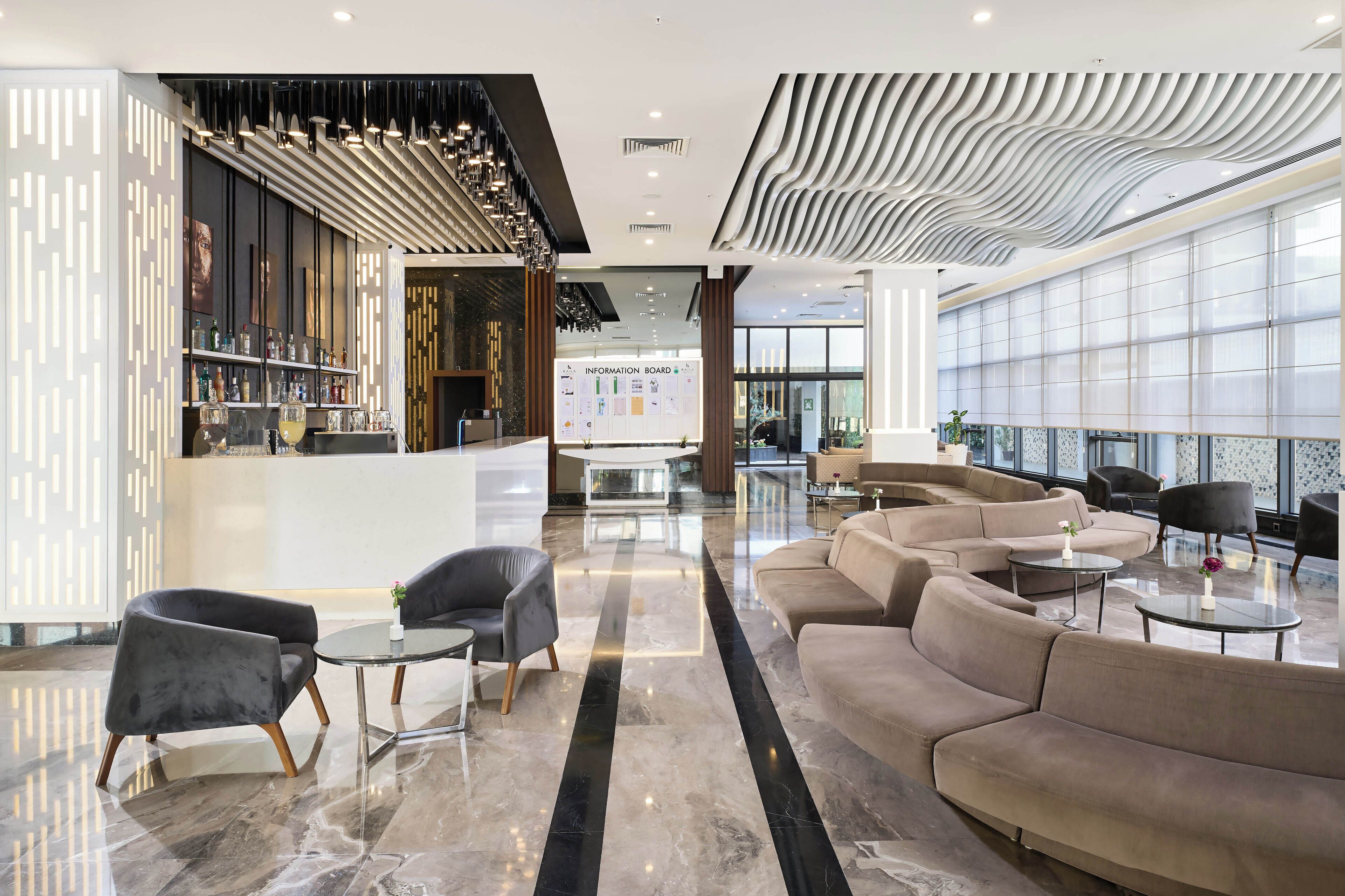 Un vestíbulo moderno con mostrador de recepción, zona de estar y un amplio panel informativo.