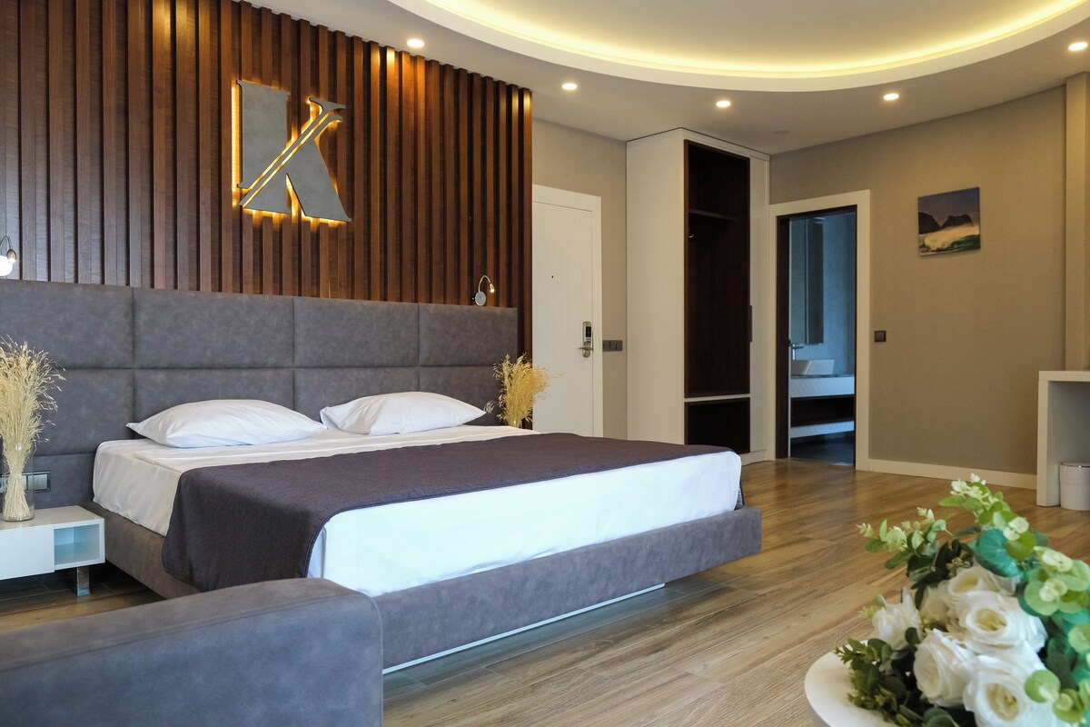 A modern bedroom with a large bed, a bedside table, and a wall-mounted light fixture.