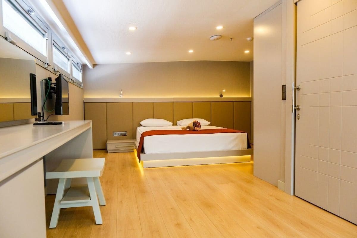 A modern hotel room with a bed, a desk, and a bench.