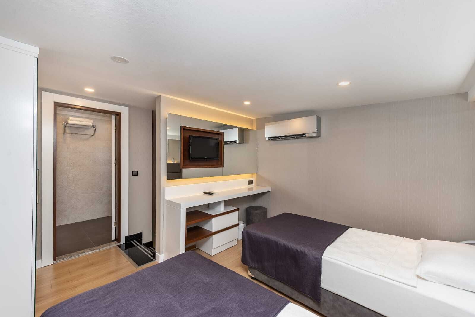 A hotel room with a bed, a desk, a mirror, and a TV.