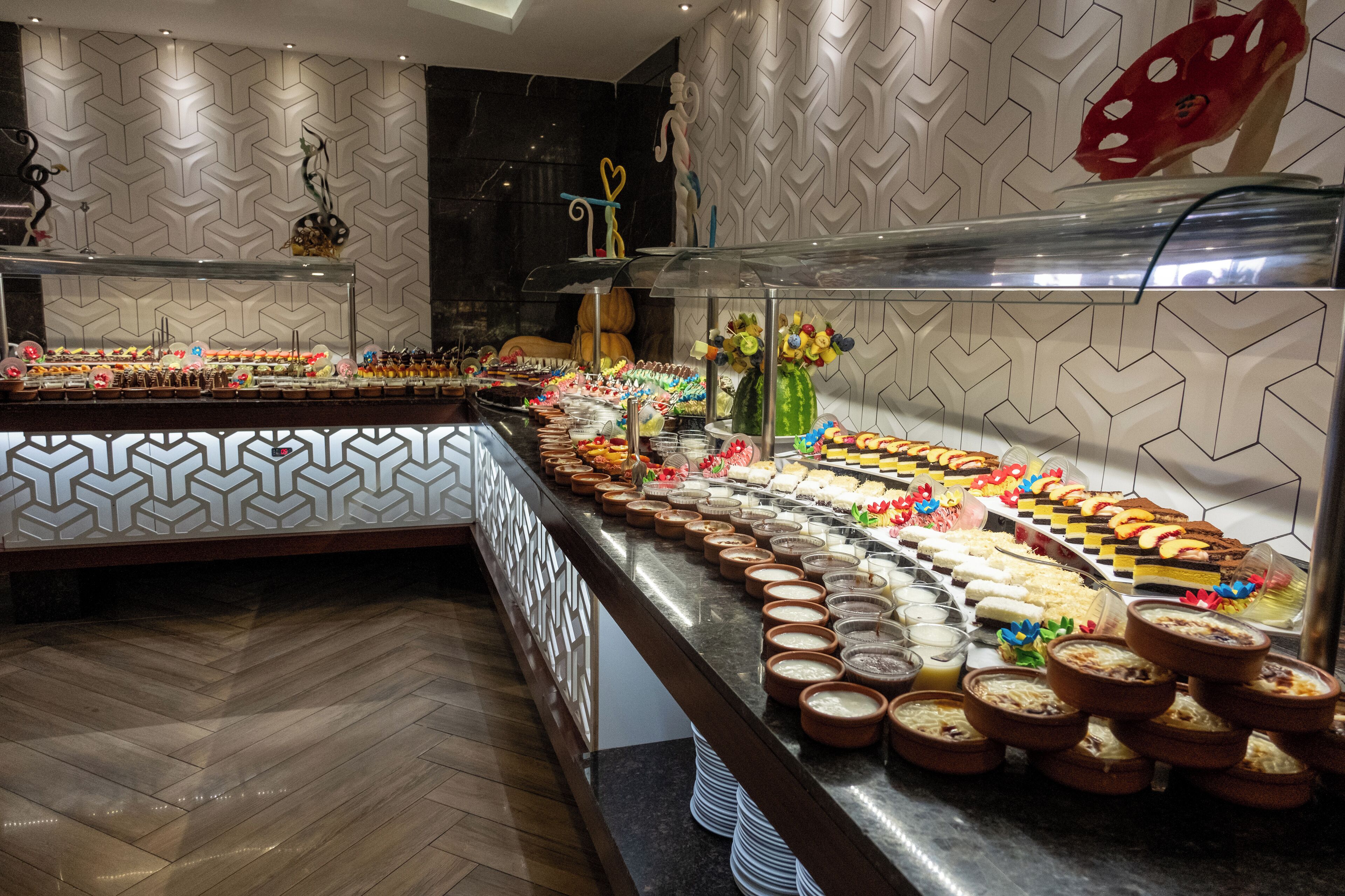 A buffet with various food items and a decorative wall with a geometric pattern.