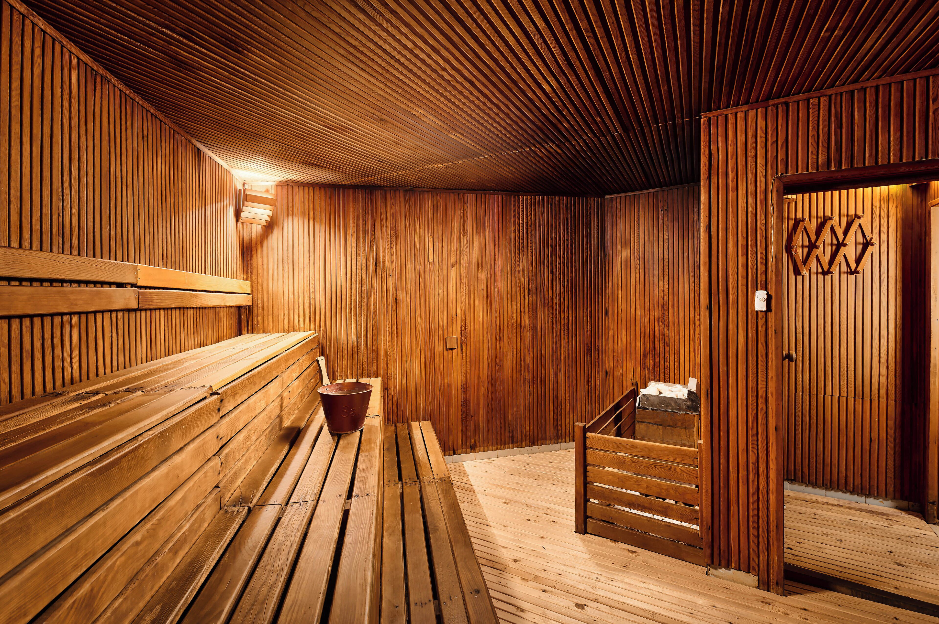 Uma sala de sauna com bancos de madeira e um balde em um banco.