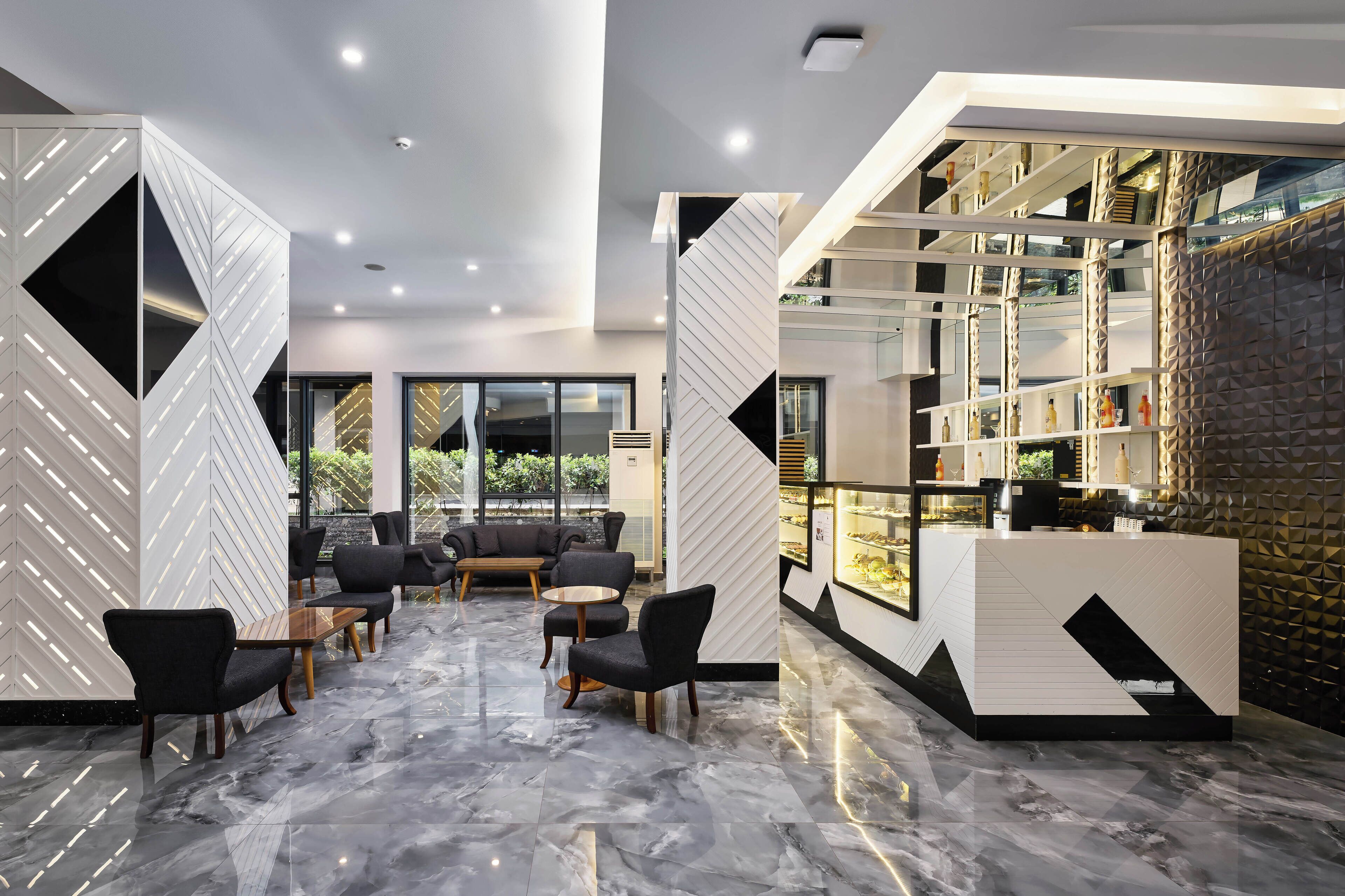 A modern lobby with a reception desk, seating area, and large windows.