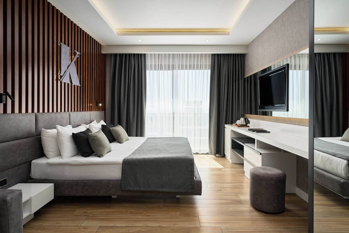 A modern hotel room with a large bed, a desk, and a television.
