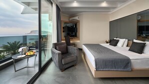 Una habitación de hotel moderna con balcón, una cama, una silla y una pequeña mesa con fruta y un vaso.