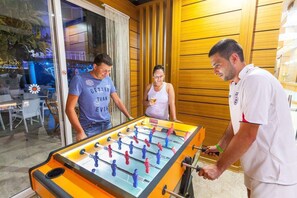 A foosball table in a room with wooden paneling and a glass door. - Galaxy Beach Hotel (Alanya)