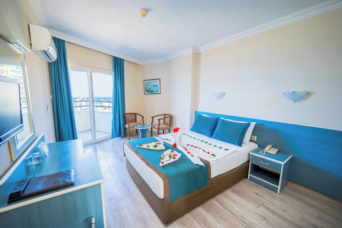 Hotellihuone, jossa on sänky, työpöytä, tuoli, pieni pöytä ja näkymä ulos.