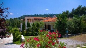 A building with a tiled roof, surrounded by greenery and a gravel path. - Giga Mar (Kassandra)