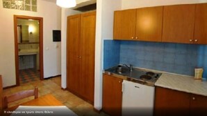 A compact kitchen with wooden cabinets, a stove, and a sink. - Giga Mar (Kassandra)