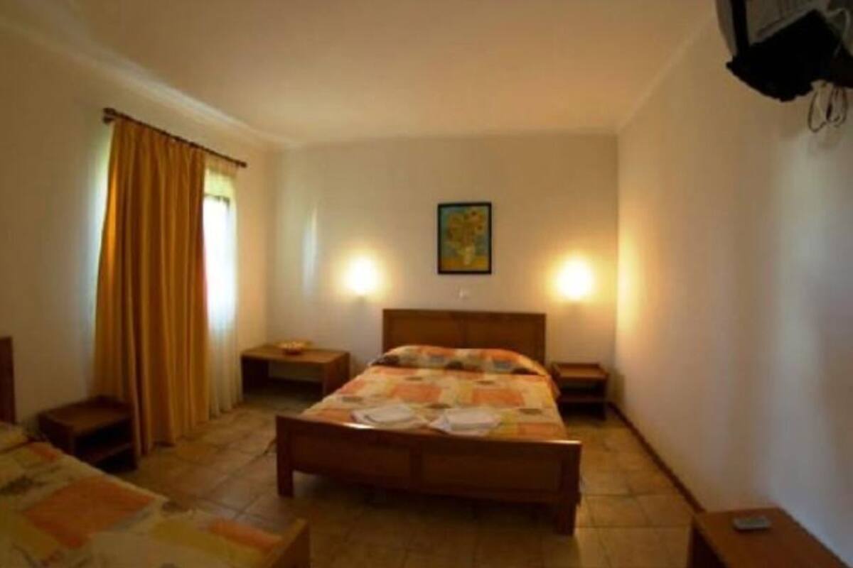 Ein Schlafzimmer mit einem hölzernen Bett, zwei Nachttischen, einer Fensterbank, Vorhängen und einer Wandleuchte.