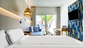 A hotel room with a large bed, a desk, a chair, a TV, and a window with a view of palm trees. - LABRANDA Hotel Golden Beach  (Pajara)
