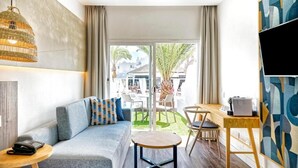 A modern hotel room with a sofa, a small round table, a desk, and a large TV. - LABRANDA Hotel Golden Beach  (Pajara)