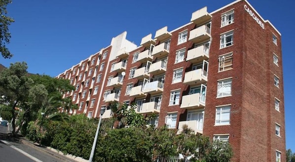 A multi-story brick building with balconies, likely a residential apartment complex.