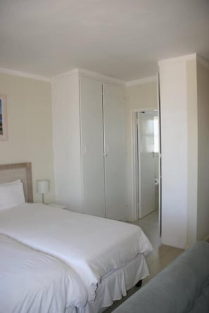 A hotel room with a large bed, a wardrobe, and a door leading to a bathroom.