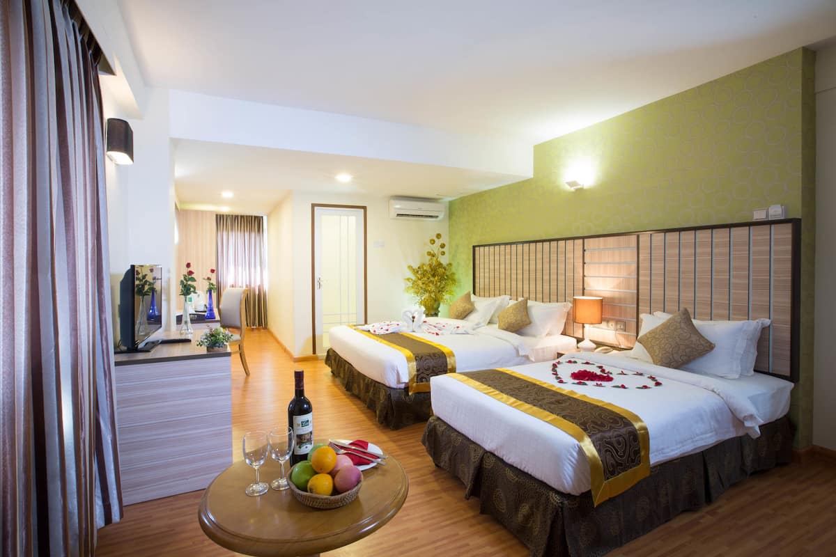 Ein Hotelzimmer mit zwei Betten, einem Essbereich mit Tisch und einem Fernseher.